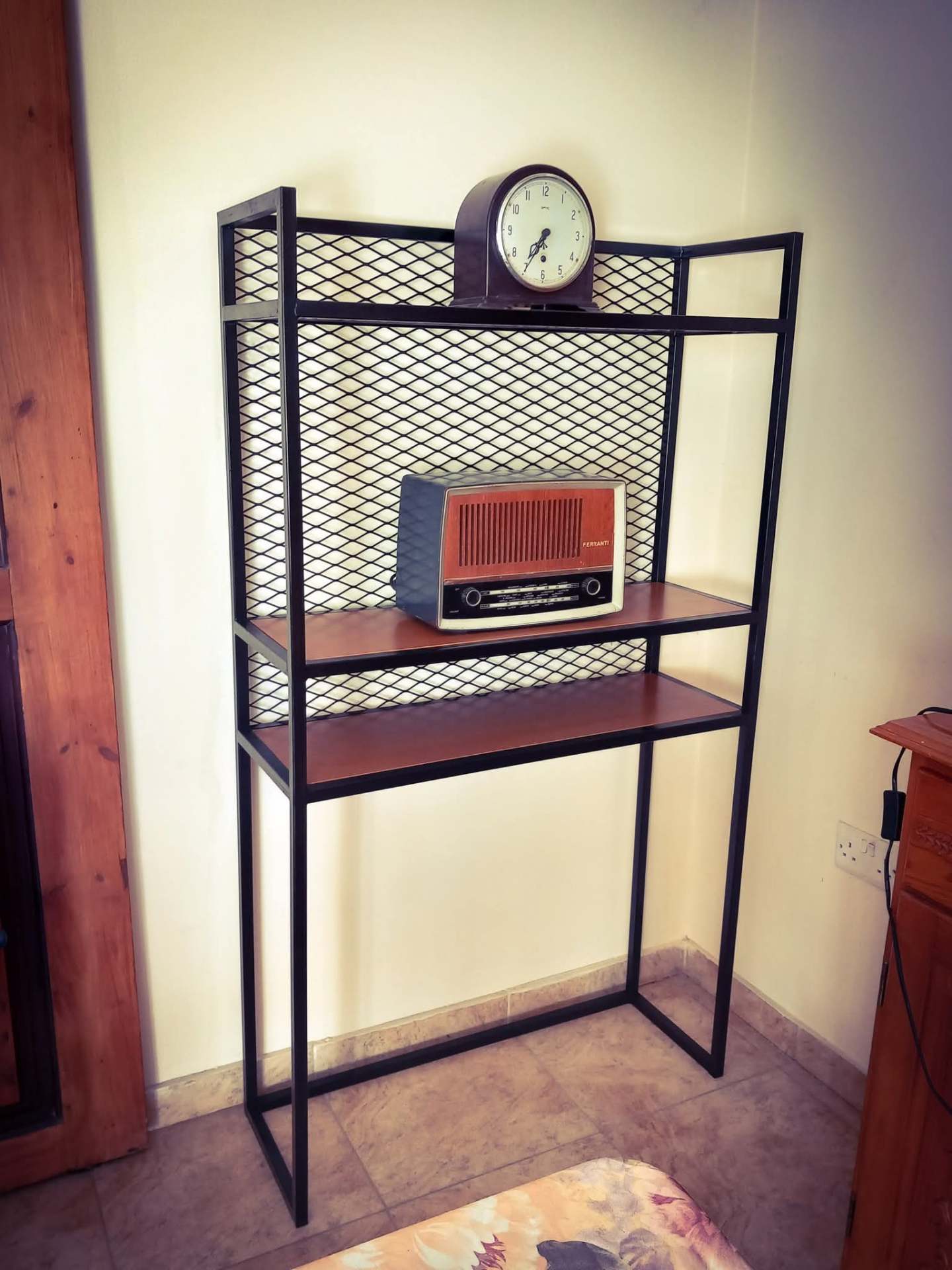 Black steel shelving unit with expanded mesh back and wooden shelves
